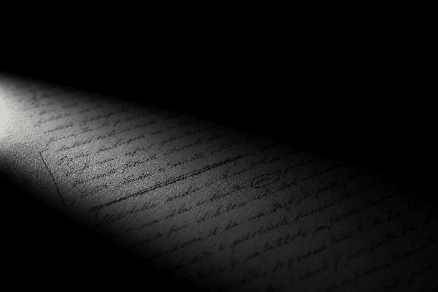 Une copie manuscrite annotée au stylo rouge, éclairée dans le noir